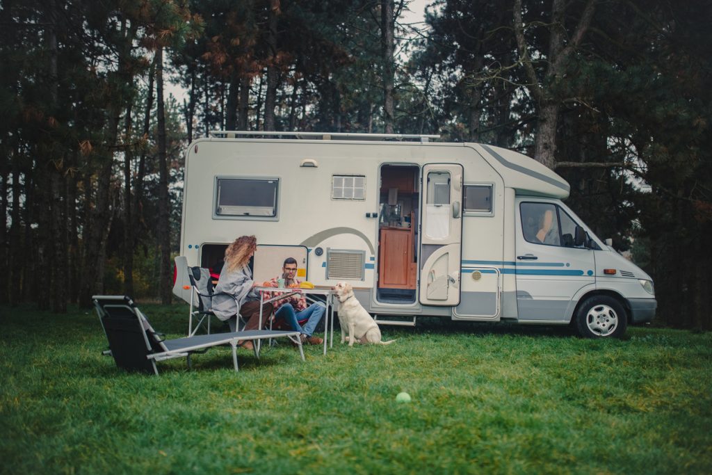 family sitting outside a customized camper with used parts